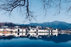 Paesaggio sereno con un lago che riflette un pittoresco paese al tramonto.