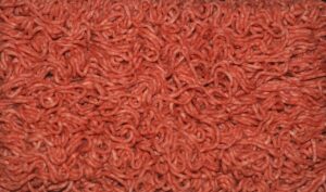 Carne macinata in vaschetta con evidenza del colore grigio sul fondo.